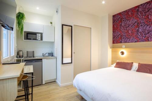 Cet appartement comprend une chambre avec un lit blanc et une cuisine. dans l'établissement Appartement 5 proche de la gare et du centre ville, à Amiens