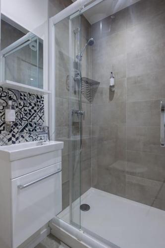 une salle de bain avec une douche avec une porte vitrée dans l'établissement Appartement 5 proche de la gare et du centre ville, à Amiens