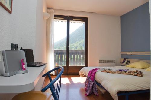 a room with a bed and a desk with a window at VTF Les Econtres in Chamonix-Mont-Blanc
