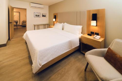 a bedroom with a large white bed and a chair at Holiday Inn Tijuana Zona Rio, an IHG Hotel in Tijuana