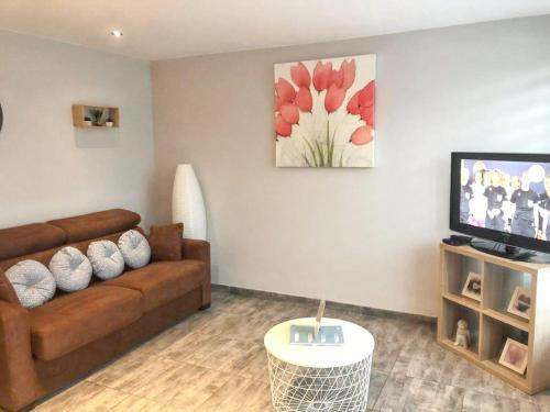 een woonkamer met een bank en een tv bij One bedroom house with shared pool enclosed garden and wifi at Hamois in Hamois
