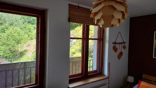 a room with two windows and a chandelier at Apartament Międzygórski in Miedzygorze