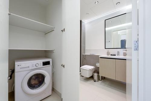 uma casa de banho branca com uma máquina de lavar roupa e um lavatório em Stayis -Spacious & Luxury 1 Bedroom room Apartment em Dubai
