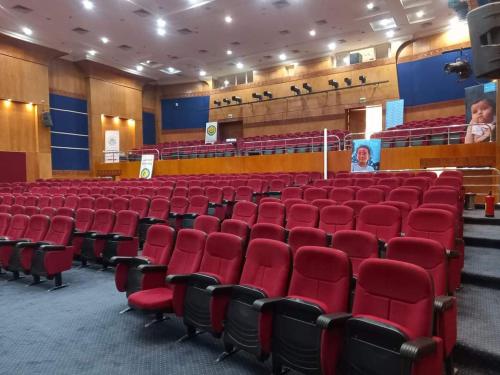 an empty auditorium with red chairs in a theatre at نزل الشباب in Ţawd