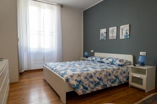 a bedroom with a bed with a blue comforter and a window at Elegante appartamento nel cuore di Omegna in Omegna