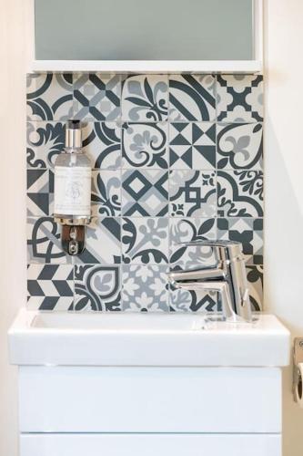 La salle de bains est pourvue d'un lavabo et d'un mur à motifs. dans l'établissement Appartement 6 proche de la gare et du centre ville, à Amiens