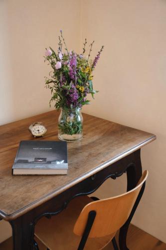 a table with a vase of flowers and a laptop at Der Pfarrhof in Hartberg