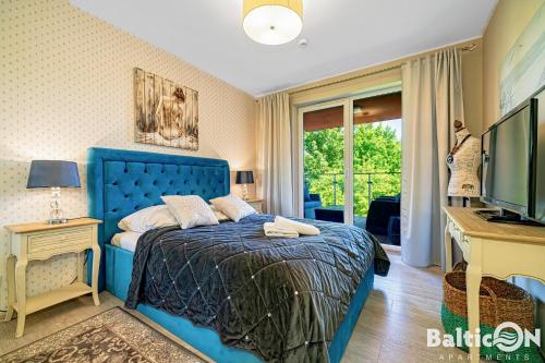 コウォブジェクにあるApartamenty BalticON Polanki Parkのデスク、テレビが備わる客室の青いベッド1台分です。
