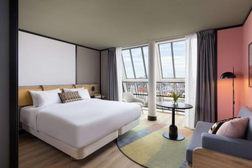 um quarto com uma grande cama branca e um sofá em Avani Museum Quarter Amsterdam Hotel em Amesterdão