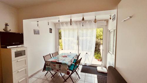 une salle à manger avec une table et des chaises et une fenêtre dans l'établissement Appart du parc, emplacement rêvé, à Saint-Jean-de-Monts