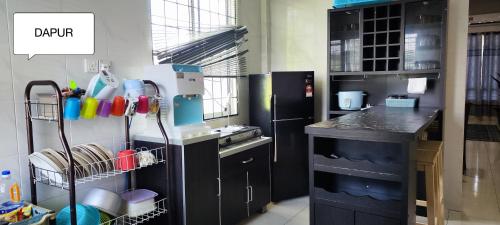 a kitchen with a sink and a black refrigerator at Farwis Homestay in Mukah