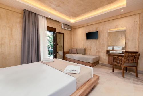 a bedroom with a bed and a desk and a television at Odyssey Accommodation - Apartments in Pefkochori