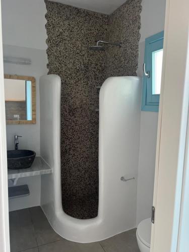 a bathroom with a shower with a wall covered in gravel at Studios Venetsanos in Koufonisia