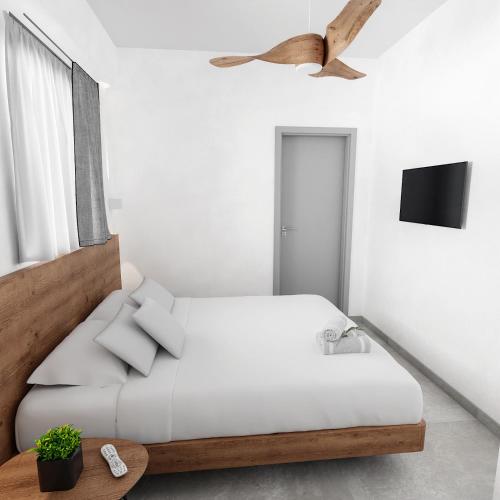 a white bedroom with a bed and a tv at Viva Mare Studios in Astypalaia Town