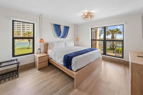 a bedroom with a bed and two windows at Saida II Beachfront Oasis in South Padre Island