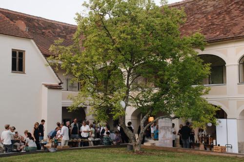 a group of people standing outside of a building with a tree at Der Pfarrhof in Hartberg