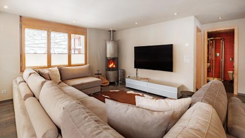 a living room with a large couch and a flat screen tv at Casa Della Luce Apartments by Zermatt Premium Apartments in Zermatt