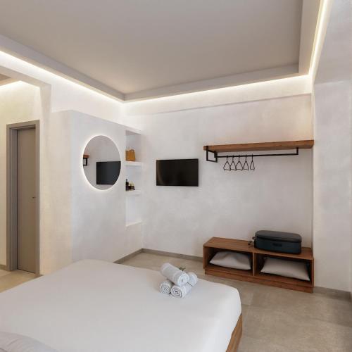 a white bedroom with a bed and a tv at Viva Mare Studios in Astypalaia Town