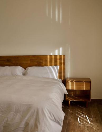 une chambre avec un grand lit avec une tête de lit en bois dans l'établissement Casa Valeria, à San Miguel de Allende