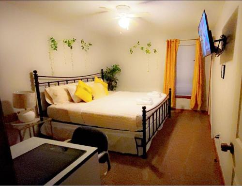 1 dormitorio con 1 cama con almohadas amarillas y TV en B1 Guest House en Hope Mills