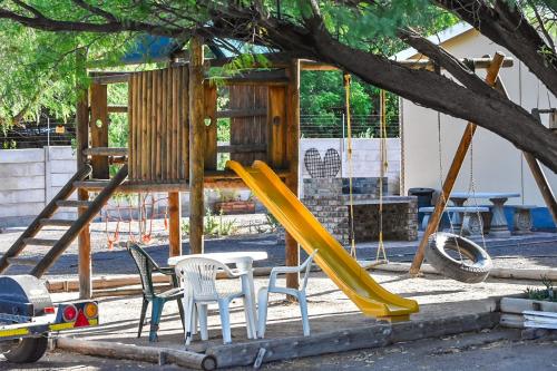 a playground with a yellow slide and chairs at En Route in Beaufort West