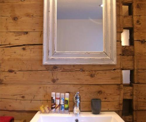 a bathroom with a sink and a mirror on a wooden wall at Boutique Hotel The River House in Andermatt