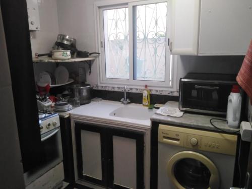 a kitchen with a sink and a washing machine at Charmante Maisonnette avec Jardin et arbis voiture in Ez Zahra