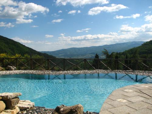 a pool with a fence and a waterfall at Borgo I Tre Baroni - Spa Suites & Resort in Poppi
