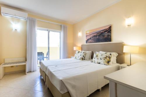 a bedroom with a large bed and a large window at Vila Marachique Torralvor in Alvor