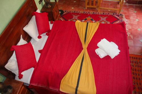 a bed with red and yellow blankets and pillows at Riad Soleil du Monde in Zagora