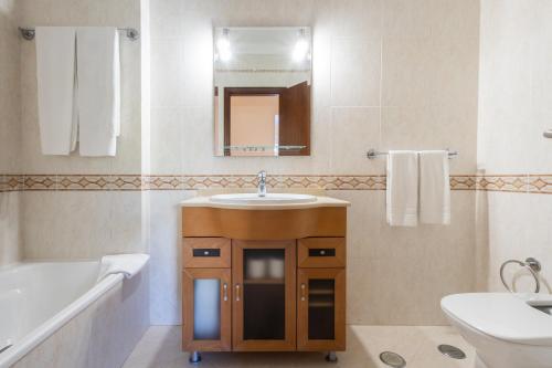 a bathroom with a sink and a mirror and a tub at Vila Marachique Torralvor in Alvor