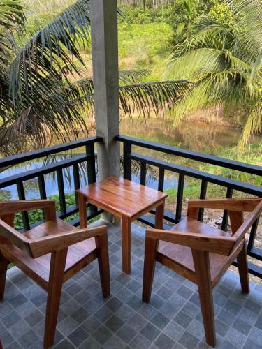 Green Mountain Resort Koh Yao في كو ياو ياي: ثلاثة مقاعد خشبية وطاولة على شرفة