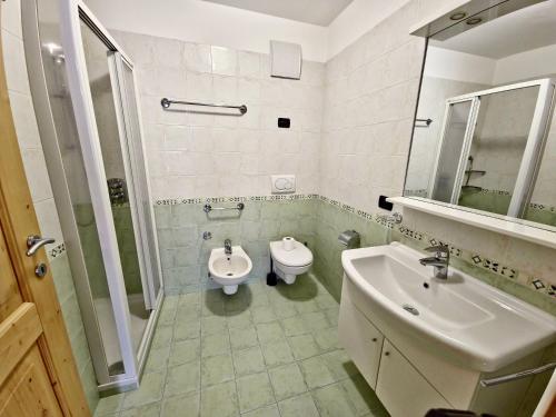 W łazience znajduje się umywalka, toaleta i lustro. w obiekcie Alpe Di Gries Sella Ronda Dolomiti w mieście Canazei
