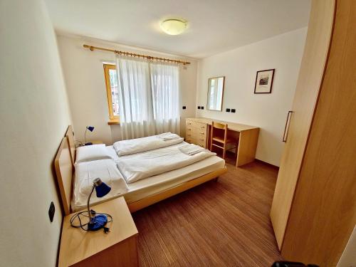 a bedroom with a bed and a desk and a window at Alpe Di Gries Sella Ronda Dolomiti in Canazei