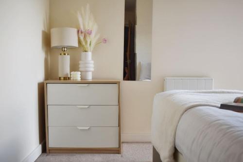 a bedroom with a bed and a dresser with a lamp at Cosy two bedroom in Romford in Romford