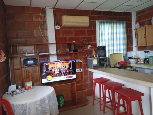eine Küche mit einem TV und einer Theke mit Stühlen in der Unterkunft A orillas del paraiso in Playas