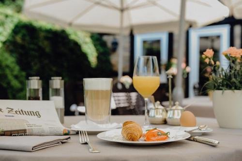 uma mesa com um prato de comida e um copo de sumo de laranja em Romantik Hotel Köllners Landhaus em Celle