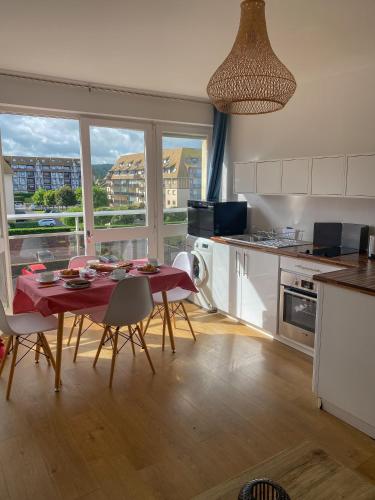 une cuisine avec une table et des chaises et une cuisine avec une fenêtre dans l'établissement Le petit Villers, à Villers-sur-Mer