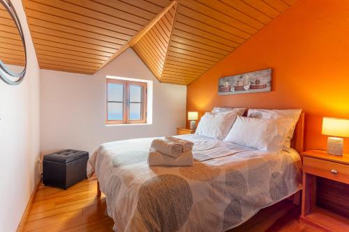 Un dormitorio con una cama grande con una pared naranja. en Refúgio do Lourinho, en Funchal