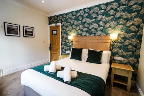 a bedroom with a large white bed with a green blanket at Gwydyr Hotel in Betws-y-coed