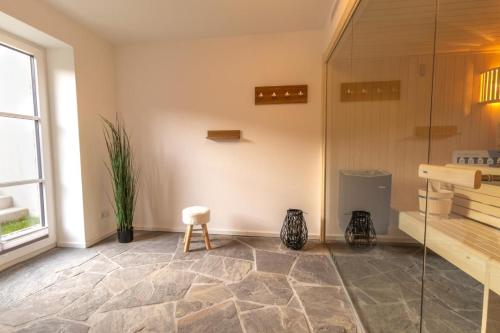 a bathroom with a glass shower and a stool at Villa BalticBliss auf Rügen - direkt am Golplatz mit Sauna und Jacuzzi in Lohme