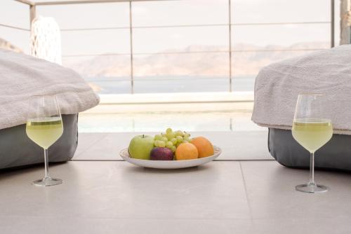 two glasses of white wine and a bowl of fruit at Gestema Luxury Residences in Kalymnos