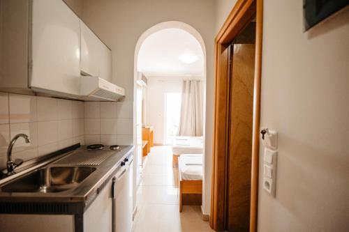 une cuisine avec un évier et une porte ouverte dans l'établissement Hotel Marialena, à Potos