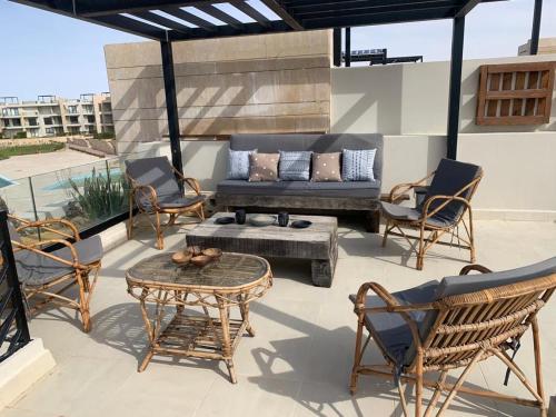 eine Terrasse mit Stühlen, einer Couch und einem Tisch in der Unterkunft Caesar Bay Resort Ras Al Hekma in Dawwār Abū Duray‘ah ‘Abd al Karīm