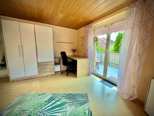 an office with a desk and a sliding glass door at neXt doOr Donau Gästezimmer und Suite in Wurmlingen