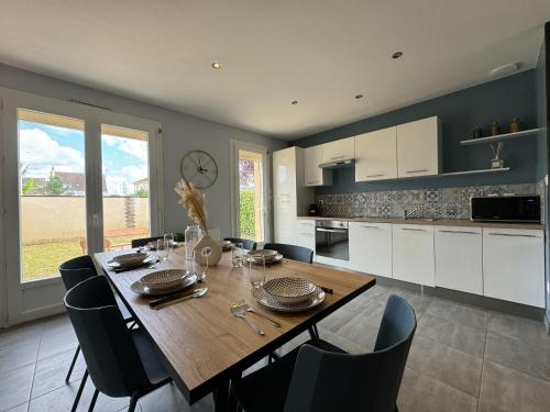 une cuisine et une salle à manger avec une table et des chaises en bois dans l'établissement Maison des tourelles - 6pers - WiFi - Rêve au Mans, à Arnage