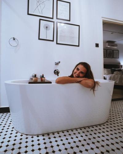 a woman laying in a white tub in a bathroom at Villa Lé Maas Tota by 98 Acres in Koslanda