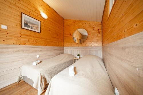two beds in a room with wooden walls at MAX Apartamenty - Pokoje - Domki - Restauracja - Basen in Mielno
