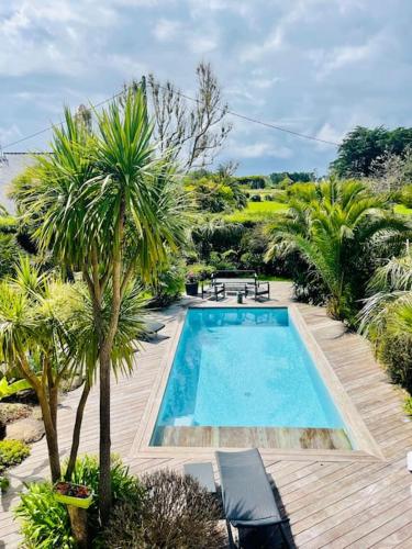 - une piscine bordée de palmiers sur une terrasse en bois dans l'établissement Villa rospico, 200m de la plage avec piscine, à Névez