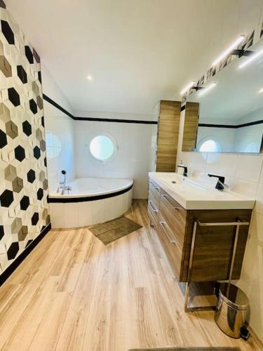 une grande salle de bain avec une baignoire et un lavabo dans l'établissement Villa rospico, 200m de la plage avec piscine, à Névez